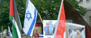 Israelische und palästinensische Fahne friedlich nebeneinander? Nein, bei diesem Foto von Demonstranten der verschiedenen Lager am sogenannten Al-Quds-Tag in Berlin täuscht die Perspektive. 