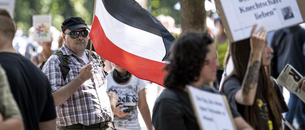 Ein Teilnehmer der Demonstration gegen die Corona-Beschränkungen trägt eine Flagge des Deutschen Reiches. 
