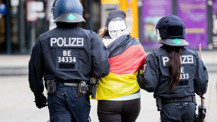 Polizisten führen bei einer Demonstration gegen die Corona-Maßnahmen auf dem Alexanderplatz eine Frau ab.