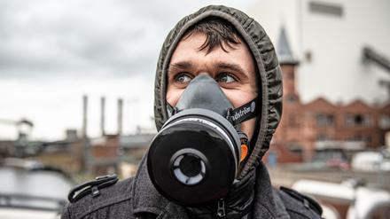  Ein Demonstrant mit Atemschutzmaske steht auf der Föhrer Brücke am Kraftwerk Moabit.