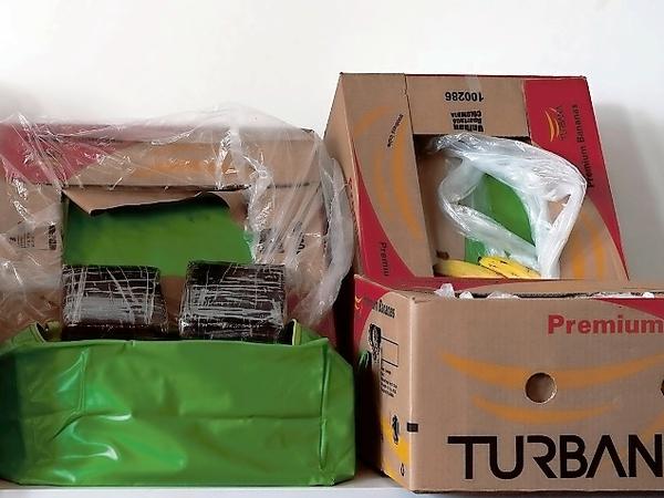 Kisten mit Bananen und schwarzen Päckchen stehen am 04.05.2015 im Landeskriminalamt Berlin auf einem Tisch. In den Banankisten aus Berliner Aldi-Supermärkten sind große Mengen Kokain entdeckt worden.