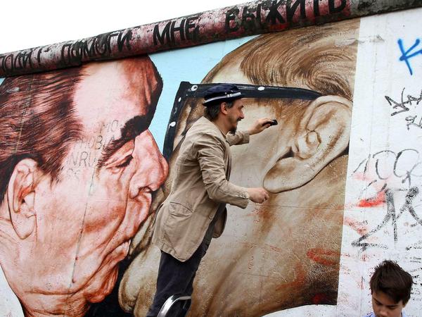 Der russische Mauerkünstler Dimitri Vrubel schrubbt am Sonntag Leonid Breschnew und Erich Honecker auf seinem berühmten Bruderkussgemälde. 