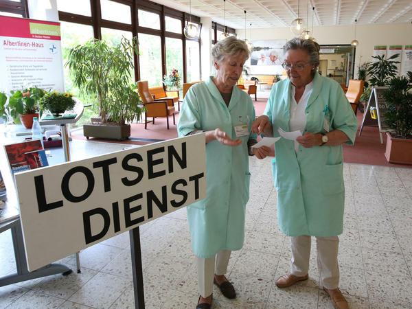 Zwei ehrenamtliche Mitgliederinnen des Kranken-Lotsendienst unterhalten sich in einem Hamburger Krankenhaus.
