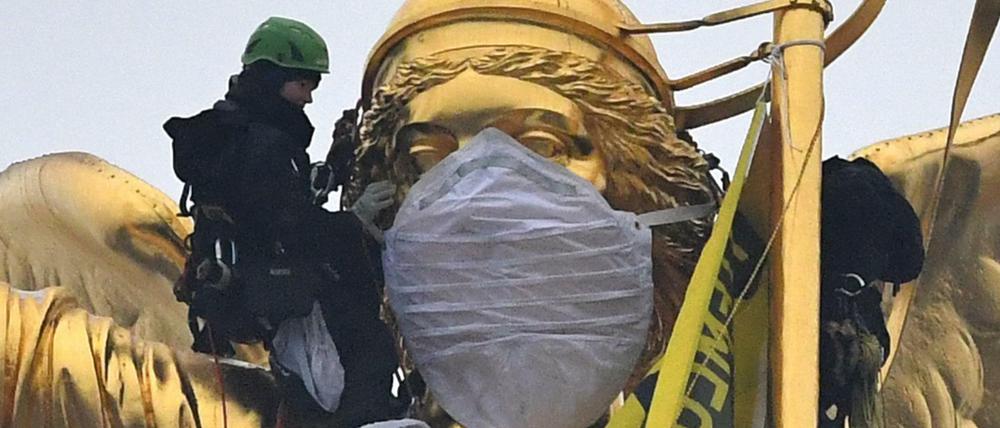 Aktivisten der Umweltschutzorganisation Greenpeace haben eine Atemschutzmaske der Statue auf der Siegessäule übergezogen. 