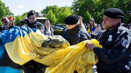 Polizisten wickelten am Sonntag eine große Ukrainische Fahne bei einer Gedenkveranstaltung vor dem Sowjetischen Ehrenmal im Tiergarten ein. 