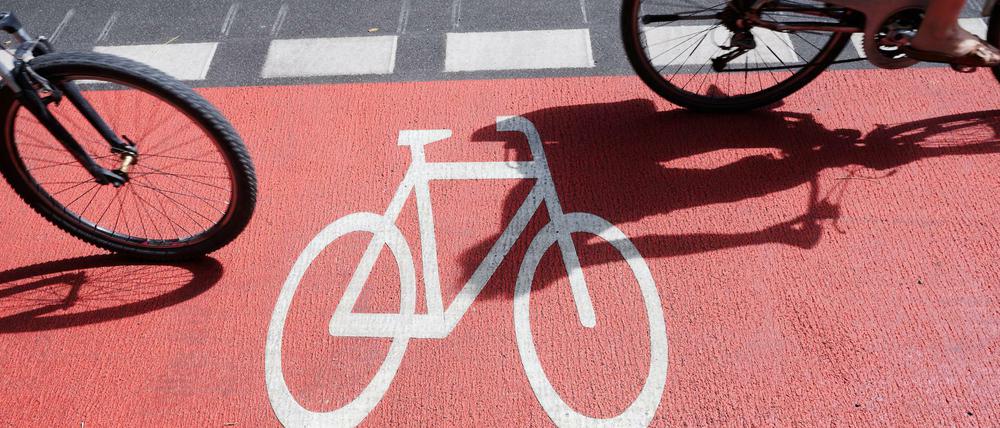 Zwei Personen nutzen mit ihren Drahteseln den rot gekennzeichneten neuen Fahrradstreifen am Kottbusser Damm. Wie kann der Ausbau der gesicherten Wege schneller gehen?