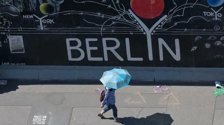 Eine Touristin nutzt einen Regenschirm als Schutz gegen die Sonne an der East Side Gallery im Juni 2019.