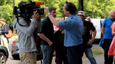 Ein Justizbeamter will die Journalisten vor dem Gericht am Filmen hindern. Im Hintergrund steht der Journalist Arndt Ginzel.