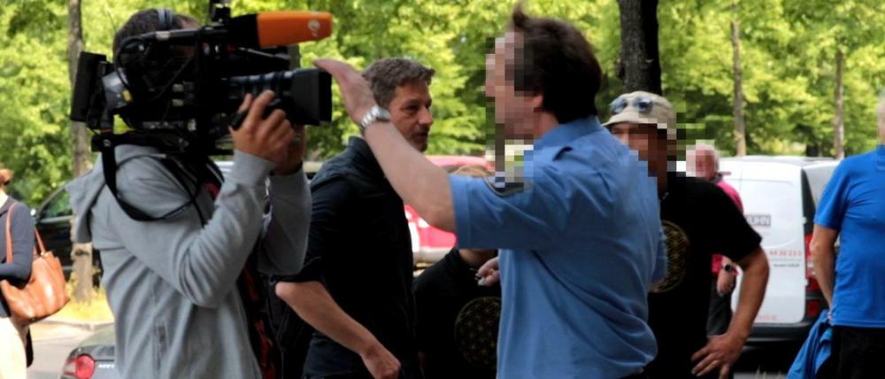 Ein Justizbeamter will die Journalisten vor dem Gericht am Filmen hindern. Im Hintergrund steht der Journalist Arndt Ginzel.