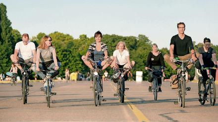 Teilnehmer eines Kurses im YogaCycling fahren auf dem Tempelhofes Feld in Berlin Fahrrad im Yogasitz.