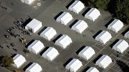 Flüchtlinge stehen zwischen exakt ausgerichteten Zelten in der ehemaligen Schmidt-Knobelsdorf-Kaserne.