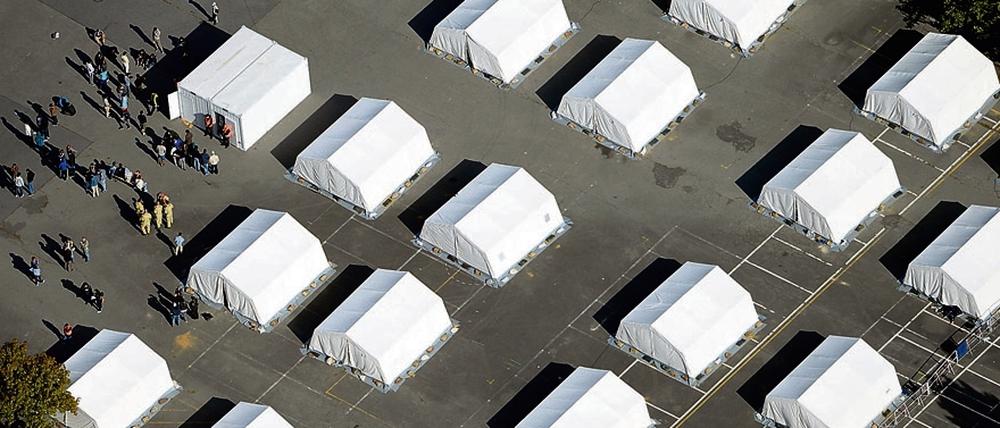 Flüchtlinge stehen zwischen exakt ausgerichteten Zelten in der ehemaligen Schmidt-Knobelsdorf-Kaserne.