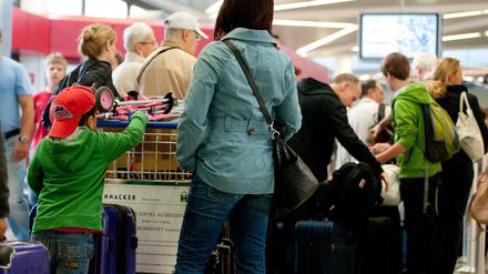 Passagiere warten mit ihrem Gepäck an einem Check-in-Schalter im Flughafen Tegel (Symbolbild).