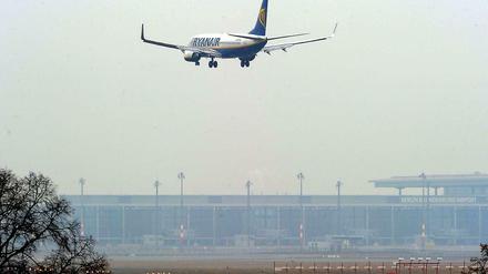 Eine Maschine der Fluggesellschaft Ryanair landet auf dem Flughafen in Schönefeld. Im Hintergrund ist der noch nicht eröffnete BER zu sehen. 