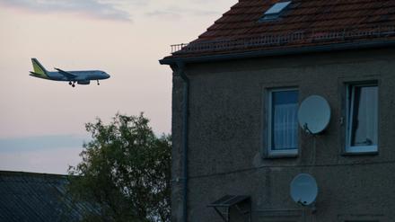 Ein Passagierflugzeug befindet sich im Landeanflug über den Dächern von Häusern im Ort Sielow unweit dem Flughafen Schönefeld. 