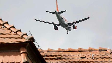 Ein Passagierflugzeug fliegt direkt über den Hausdächern. Rund um den BER hat noch kein Haus Schutzfenster nach Vorschrift.