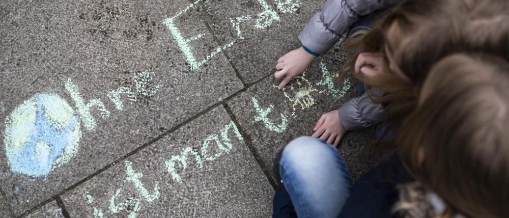 Zwei Mädchen schreiben bei der Klima-Kundgebung "Fridays for Future" am Invalidenpark den Satz "Ohne Erde ist man tot" mit Kreide auf den Boden. 