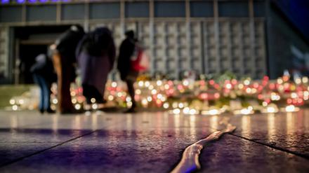 Menschen stehen bei der Gedenkfeier am vierten Jahrestag des islamistischen Anschlags 2020 auf den Weihnachtsmarkt am Breitscheidplatz am Mahnmal „Goldener Riss“, an dem viele Kerzen brennen.