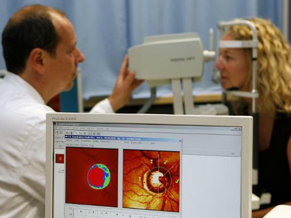 Ein Arzt der Universitäts-Augenklinik in Erlangen führt im Rahmen einer Glaukom-Vorbeugeuntersuchung an einer Frau eine Computeranalyse des Sehnervenkopfes durch.