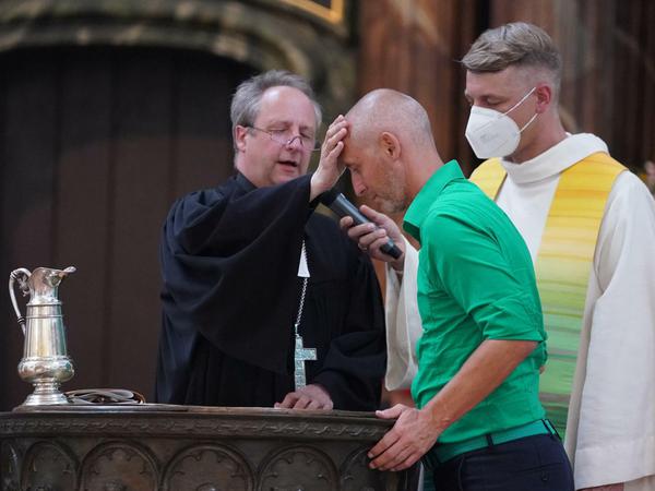Bischof Christian Stäblein tauft Ex-Fußballprofi Marcus Urban beim Gottesdienst.
