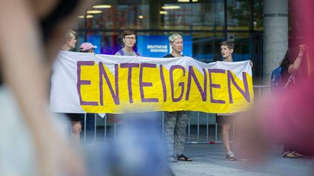 Demonstrantinnen stehen am Morgen vor dem Eingang zur Hauptversammlung des Immobilienkonzerns Deutsche Wohnen und fordern auf einem Transparent "Enteignung".