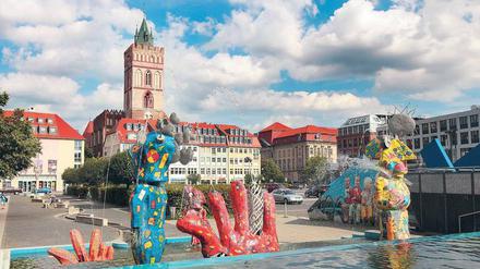 Die Comicfiguren am Frankfurter Brunnenplatz gestaltete der Künstler Michael Fischer-Art. Im Hintergrund ragt der Turm der Marienkirche auf. 