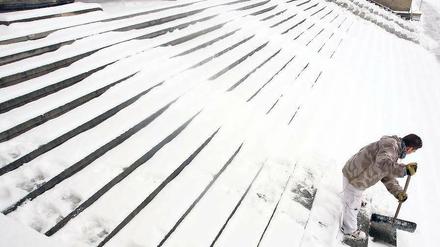 Eingeschneit. Nach neuem Schneefall wurde am Mittwoch wieder allerorten geschippt und gefegt. Auch am Alten Museum in Mitte mussten die Treppen freigeschaufelt werden. Die Meteorologen sagen für die kommenden Tage winterliche Temperaturen und weitere Schneefälle voraus. Foto: dpa/Stephanie Pilick