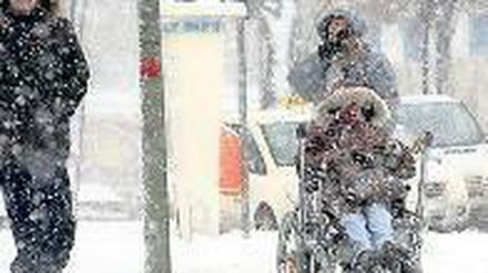 Bescheidene Wünsche. Die winterlich verschneite Stadt macht vielen das Leben schwer. Ältere Menschen bleiben derzeit aus Vorsicht lieber drinnen, und wer einen Behinderten im Rollstuhl zu bewegen hat, muss Schwerstarbeit leisten. Foto: Kumm/dpa