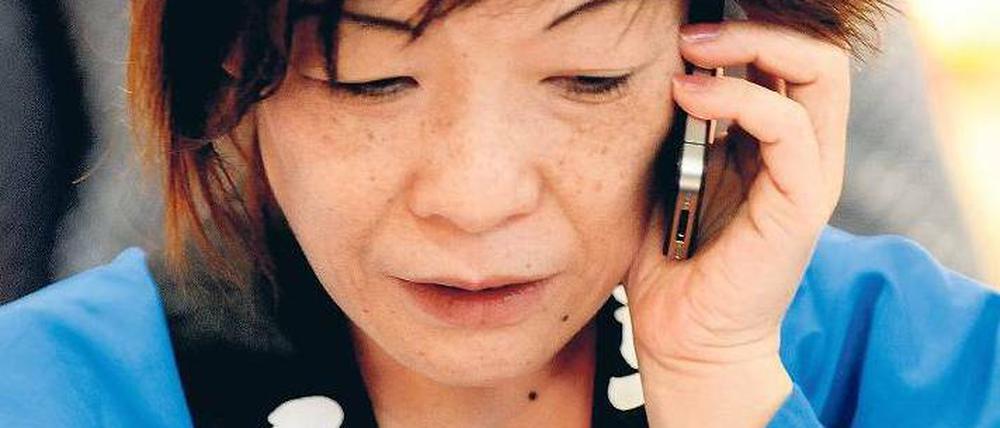 Bange Anrufe. In den Arbeitspausen bemühen sich Japans Tourismusvertreter per Handy um Infos aus der Heimat. Foto: dpa