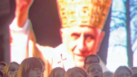 Singen und Warten. In Berlin und anderen Diözesen laufen die Vorbereitungen für den Besuch Benedikts XVI. – wie hier auf Burg Scharfenstein in Thüringen. Dort sang der Jugendchor vor einem Bild des Papstes während einer ökumenischen Lichterfeier. Foto: dapd