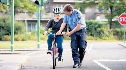 Lenkhilfe. Polizeihauptkommisar Burkhard Poschadel greift ein, damit Hagar Levim die Balance hält. Denn die junge Frau lernt das Radfahren. Foto: Adam Berry/dapd
