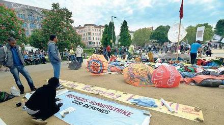 Mittendrin. Auf Transparente haben die bis vor kurzem noch hungerstreikenden Flüchtlinge am Oranienplatz ihre Forderungen geschrieben. Drumherum wird gefeiert. 