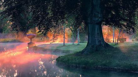 Morgennebel liegt über dem Teich zwischen Schloss Charlottenhof und den Römischen Bädern in Potsdam. 