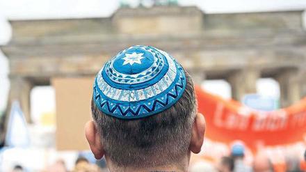 Ein jüdischer Mann mit Kippa vor dem Brandenburger Tor in Berlin.