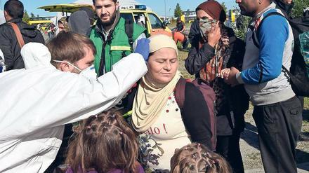 Erste Hilfe. Ein Mediziner des Deutschen Roten Kreuzes untersucht am Bahnhof Schönefeld eine Frau aus Syrien, die mit dem Zug aus München angekommen ist. 