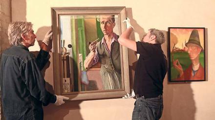 Letzte Handgriffe. Heinrich Harry Deierlings „Selbstporträt im Spiegel“ wird in die Ausstellung eingefügt. Konrad Adolf Lattners Mann mit Hut hängt schon. 