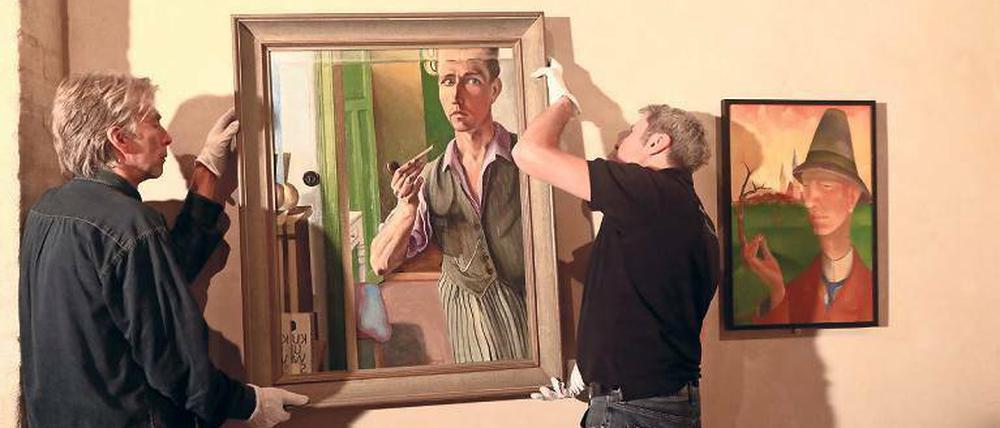 Letzte Handgriffe. Heinrich Harry Deierlings „Selbstporträt im Spiegel“ wird in die Ausstellung eingefügt. Konrad Adolf Lattners Mann mit Hut hängt schon. 