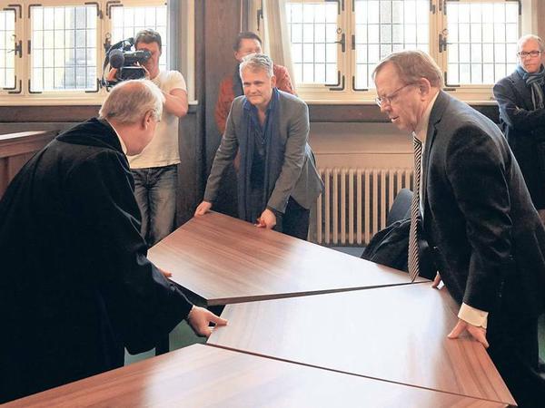 Tischerücken. Richter Sommerfeld (li.), Intendant Woelffer und Anwalt Geulen schaffen mehr Platz für Zuhörer im Gerichtssaal. 