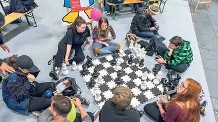 Locker im wahren Leben. Junge Messegäste spielen Mega-Schach am Boden. Drumherum werben zahlreiche Aussteller und Initiativen um das Interesse der jungen Besucher.