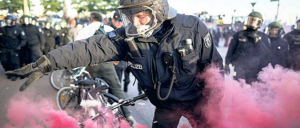 Ein Polizist entfernt eine Rauchbombe während der G20 Welcome to Hell -Demonstration. 
