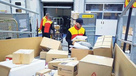 Zupackend. Mitarbeiter der Deutschen Post DHL in der Zustellbasis Marzahn laden die von einer Anlage automatisch sortierten Pakete in ihre Fahrzeuge. 