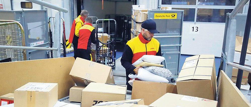 Zupackend. Mitarbeiter der Deutschen Post DHL in der Zustellbasis Marzahn laden die von einer Anlage automatisch sortierten Pakete in ihre Fahrzeuge. 
