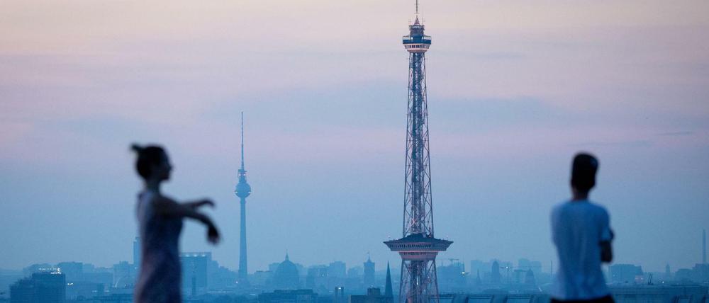 Besucher warten an einem heißen Tag auf dem Drachenberg auf den Sonnenaufgang über Berlin.