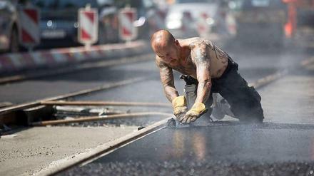 Heiße Angelegenheit: Ein Arbeiter hantiert mit frischem teer an Straßenbahngleisen.