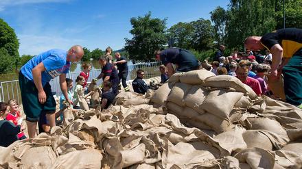 Freiwillige Helfer schichten Sandsäcke aufeinander - Zivilcourage in Sachsen