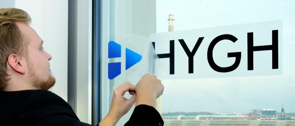 HYGH-Hardware-Chef Antonius Link klebt einen Aufkleber mit Firmenlogo an ein Bürofenster.