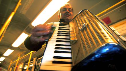 Mann mit Akkordeon macht Musik in der U-Bahn.