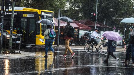 Menschen laufen mit Regenschirmen durch Berlin. (Symbolbild)
