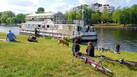 Idylle oder Ärgernis? Am Urbanhafen sitzen die Kreuzberger gern in der Sonne. Viele Uferwanderer können jedoch beim Anblick des verwahrlosten "Theaterschiffs Tau" schwer entspannen.