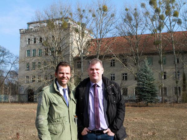 Firmenchef Robert Dahl (l) und der Bürgermeister von Elstal, Holger Schreiber (parteilos) auf dem ehemaligen Militärgelände. Im Hintergrund der Löwenturm, der erhalten bleiben soll.